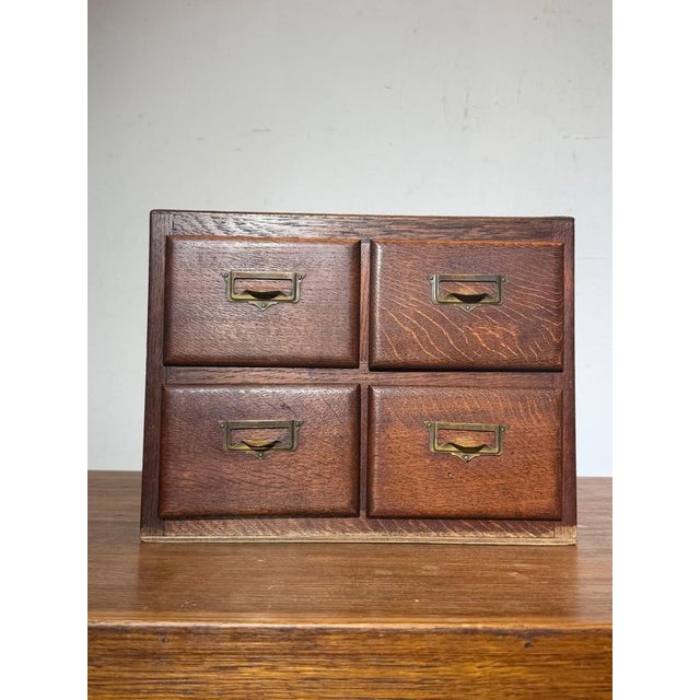 Compact wooden drawer cabinet crafted in solid oak, featuring four drawers fitted with original recessed brass label...