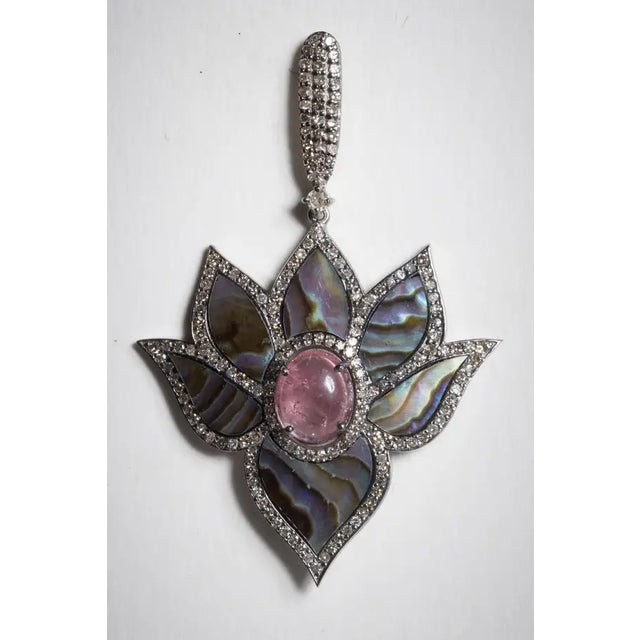 A magnificent pair of dangle earrings in a lotus flower motif with abalone petals surrounded by round, brilliant cut...