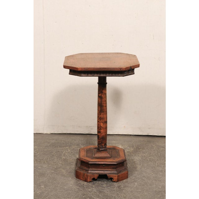 A small-sized English wooden pedestal table from the 19th century. This antique side table from England features an...