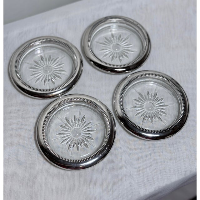 Elegant set of vintage glass coasters featuring a finely cut sunburst motif framed by silver-tone metal rims. A refined...