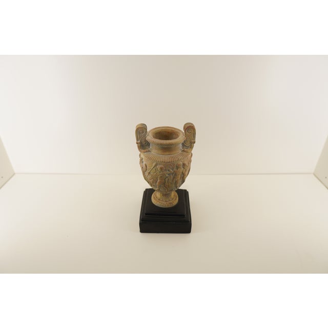 This decorative handled jar features a soft white and pink finish with sculptural detailing and is mounted on a...