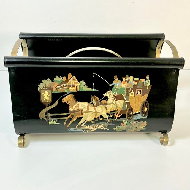 This is a fun hand painted metal tole magazine rack from the 1950s. It features a Stagecoach motif on a black metal...
