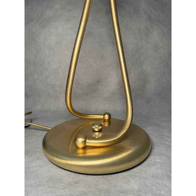 Elegant Italian table lamp in a modern design with subtle retro elements. The gold-tone base has a soft, flowing...