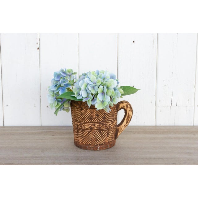 Rustic and primitive, this Himachal pot has hand-carved tribal design with a rounded handle and metal straps on the...