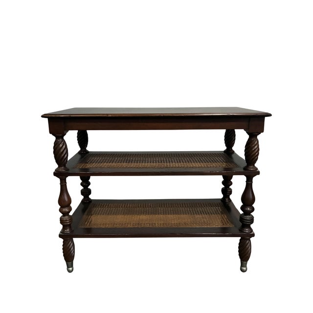 A beautifully crafted vintage Baker Furniture Milling Road three-tier console table executed in the timeless British...