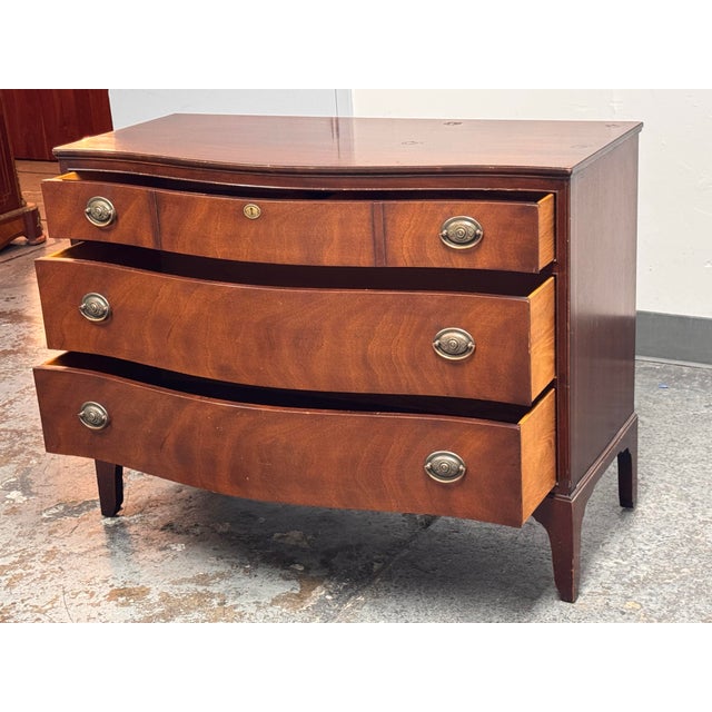 Design Plus Gallery presents a Vintage Federal-Style Mahogany Serpentine Chest of Drawers. The chest displays figured...