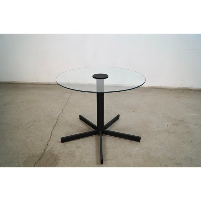 Vintage 1980's Post Modern end table for sale. It has a black metal star base with a round glass top. It's in excellent...