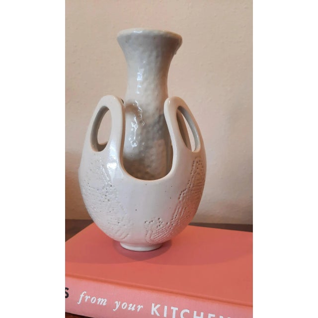 This vintage white glazed mid-century pottery vase features a unique double-wall design. An outer shell with large oval...