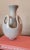 This vintage white glazed mid-century pottery vase features a unique double-wall design. An outer shell with large oval...