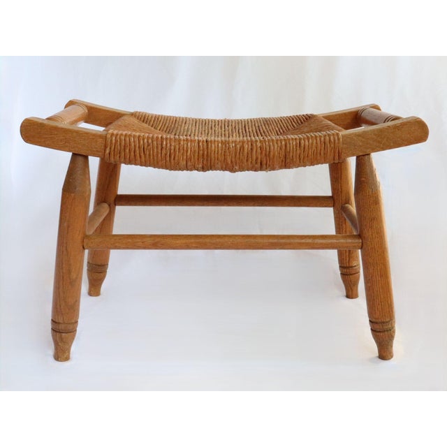 Vintage curved low stool or footstool with rush seat and stretcher leg support. Dimensions: 21"W x 12.25"D x 14"H (12.75"H...