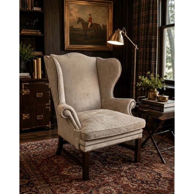 A handsome Ralph Lauren Home Devonshire wingback chair, upholstered in luxurious neutral suede and detailed with classic...