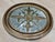 Elegant vintage oval mirror featuring an ornate giltwood frame with an intricate central floral medallion, scrolling...