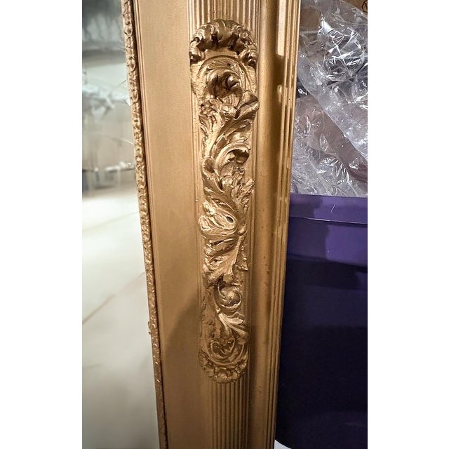 This stunning gold mirror features intricate, floral carvings along the wooden frame. The mirror itself has a slight...
