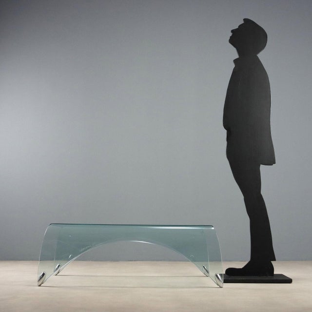 Curved glass coffee table. In good condition. This piece is attributed to the mentioned designer/maker. It has no...