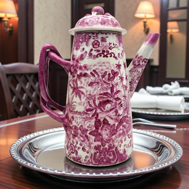 A tall lidded porcelain coffee pot presented in a saturated rose palette, defined by an intentional crackle glaze that...