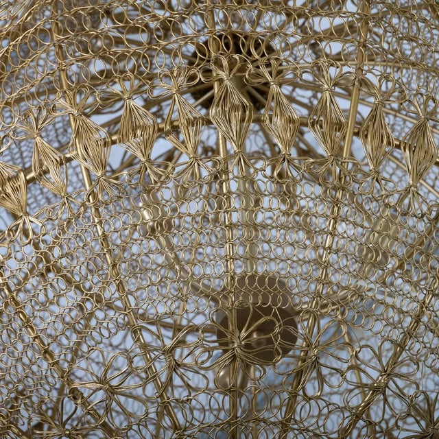 Monumental brass wire pendant with intricate wrought pattern including a flower motif.