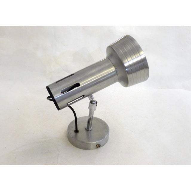 Adjustable wall spotlight with a round base, small tubular stem, and openwork spotlight shade mounted on a ball joint; all...