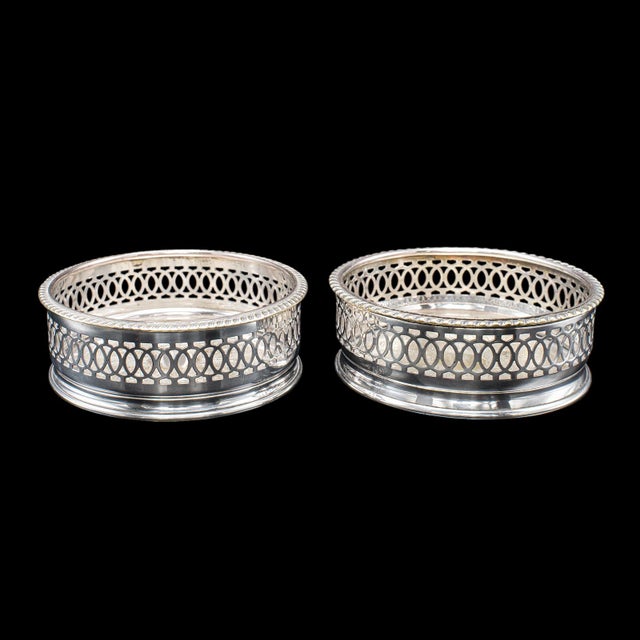 This is a vintage wine coaster duo. An English, silver plated champagne bottle stand, dating to the mid 20th century,...