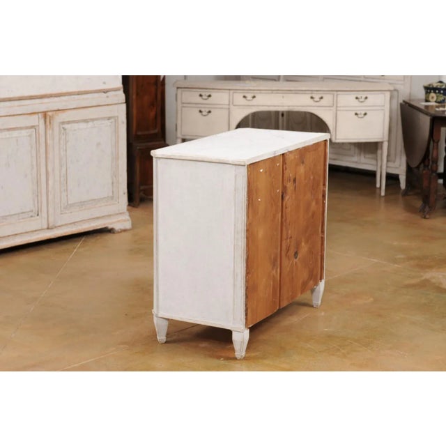A Swedish Gustavian style three-drawer chest from the 19th century with light gray painted finish, marbleized top and...