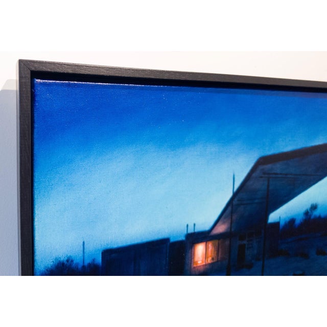 Station Blue depicts a desolate gas station under a deep blue twilight sky, evoking a sense of isolation and stillness....