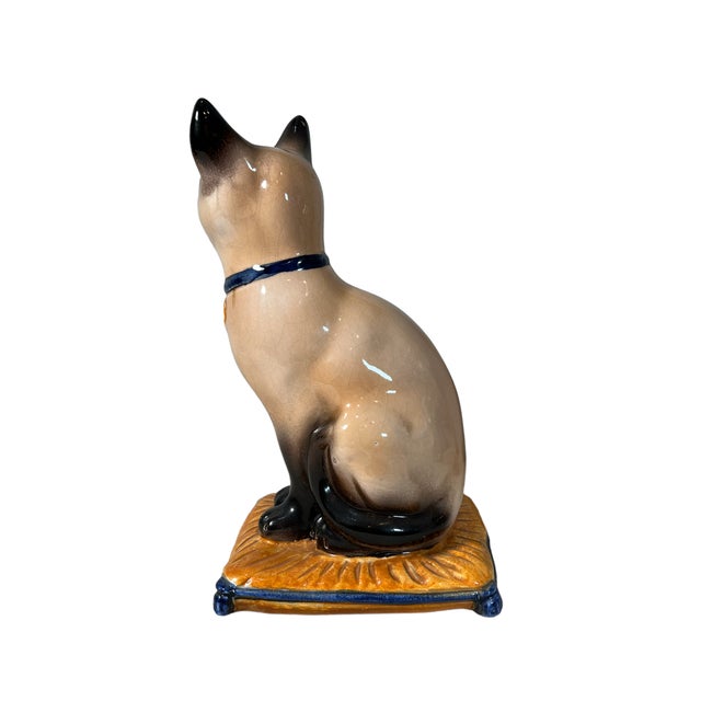 A beautifully rendered sculpture of a mischievous pampered Siamese Cat. Perched on a beautiful venetian pillow and adorned...