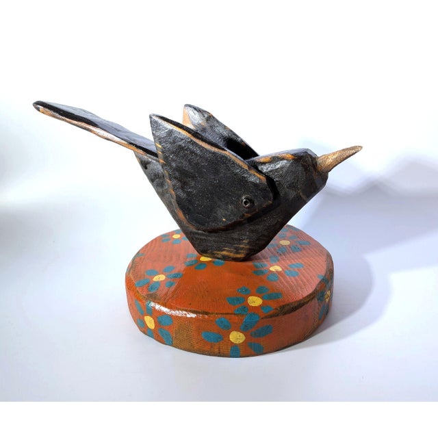 New. Original, contemporary folk art from Mikel Davison. A rustic, wooden little black bird on a daisy-flowered base....
