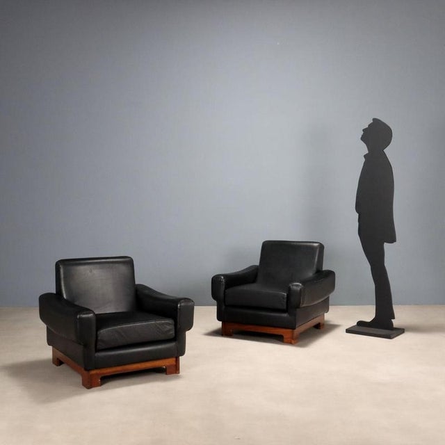 Pair of vintage armchairs with wooden frame and original black leather upholstery from the period. This piece is...