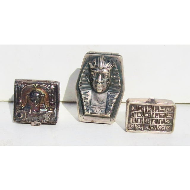 Three pill boxes from the early 1920s. The face of Pharoh on two and a series of hieroglyphs on the third. A small...
