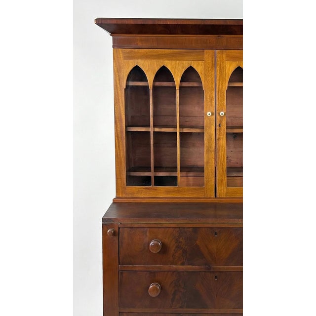American Federal/Empire period flame mahogany secretary bookcase, dating to approximately 1820–1840. Its most...