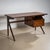 Mid-20th century desk featuring two drawers on the right side, flared legs, and a rectangular top with elegant profiling....