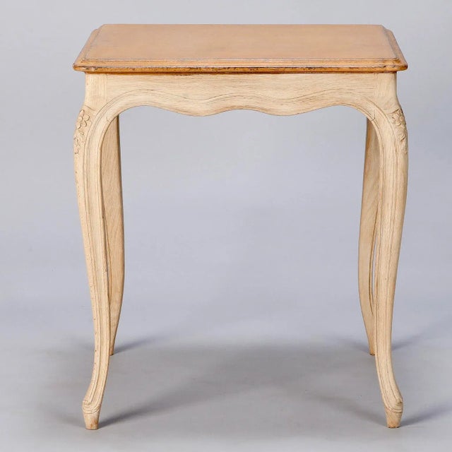 French square side table with painted top and contrasting bleached wood legs and apron with carved floral details, circa...