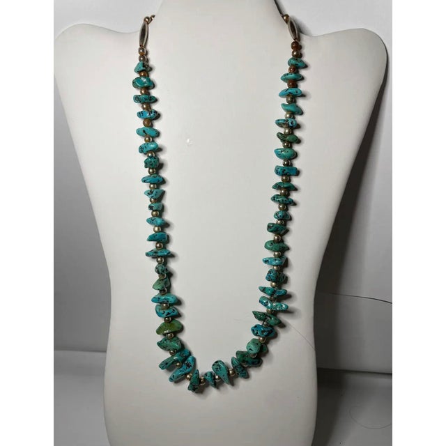 A bold Southwestern-style necklace featuring polished turquoise nuggets interspersed with round silver-tone metal beads....