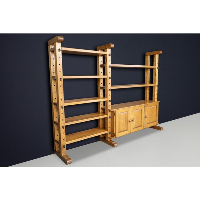 A monumental Brutalist modular shelving unit in solid oak, featuring original metal pegs and an architectural combination...