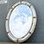 Elegant vintage Venetian-style oval wall mirror featuring a beautifully detailed gilt metal frame with mirrored border...