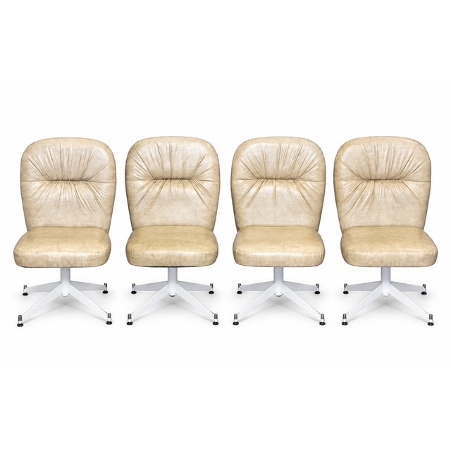 A striking set of four vintage swivel dining chairs dating to the 1970s. Each chair features a softly contoured...