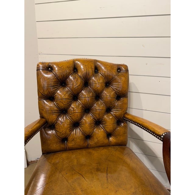 This is a lovely English leather arm chair. With a camel shaped tufted back, covered arms and decorative brass nailhead...