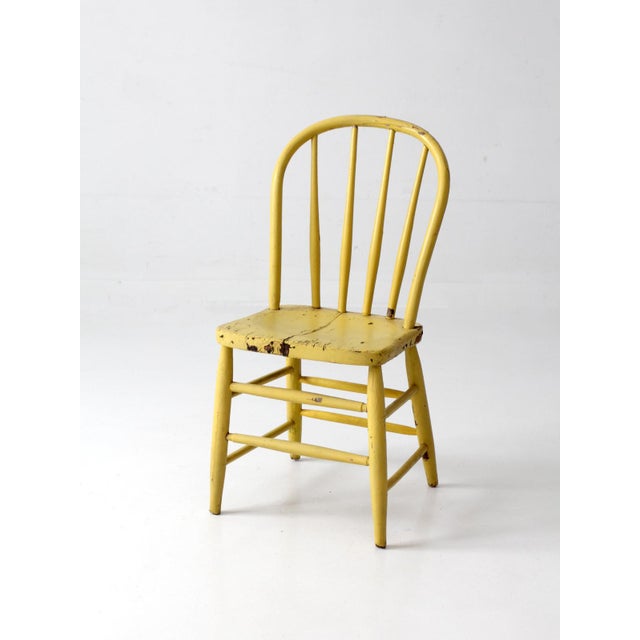 Antique Windsor spindle-back chair with a charming yellow-painted finish and classic bow-back form. Five slender spindles...