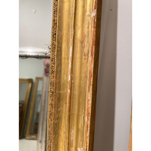 A refined 19th century French Louis XVI mirror featuring a beautifully carved gilded frame with classic neoclassical...