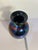This striking hand‑blown iridescent art glass vase features a deep cobalt/amethyst base color with a dramatic metallic...