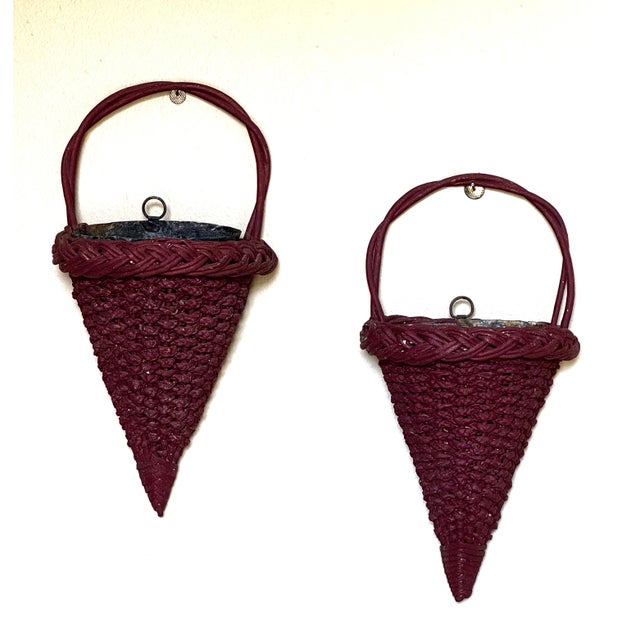 These are a pair of vintage charming burgundy wicker wall pockets feature a tapered, cone-shaped silhouette, intricately...
