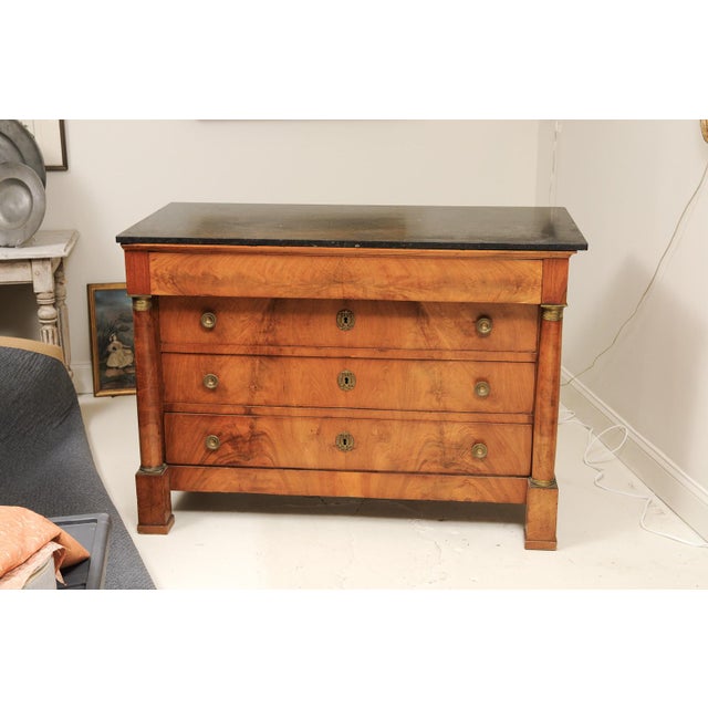 A striking example of French Empire craftsmanship, this 19th-century walnut commode combines bold architectural lines with...