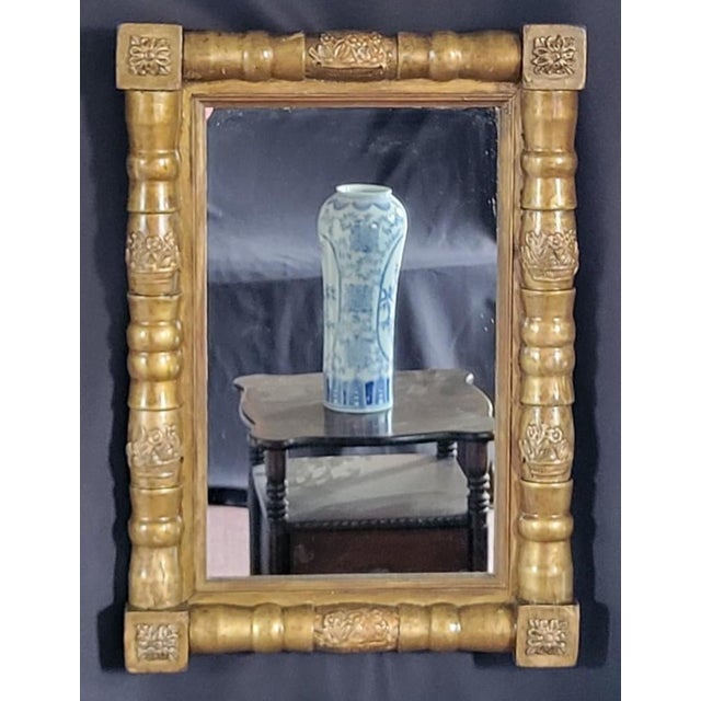 Authentic 19th-century American Federal wall mirror featuring a beautifully carved and gilded wood frame with classic...