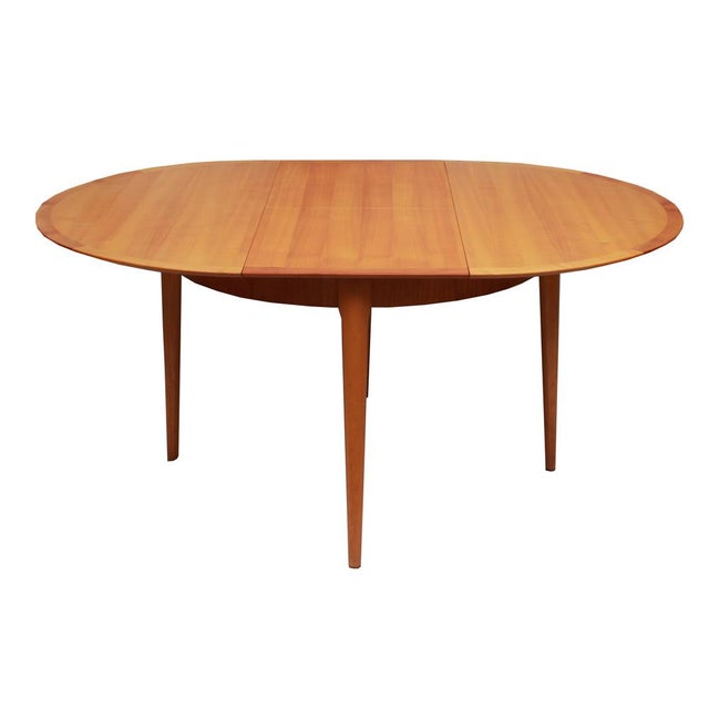 1960s dining table with a round tabletop. Veneered in cherry wood. Extendable to a maximum length of 160cm; the tabletop...