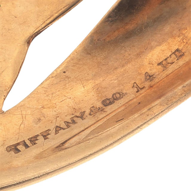 Tiffany & Co. 14K yellow gold pin features two swimming dolphins crafted with elegant, fluid lines. The pin measures...