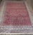 A large early 20th Century Indian Larestan Size Adjusted Rug in a predominant plum color