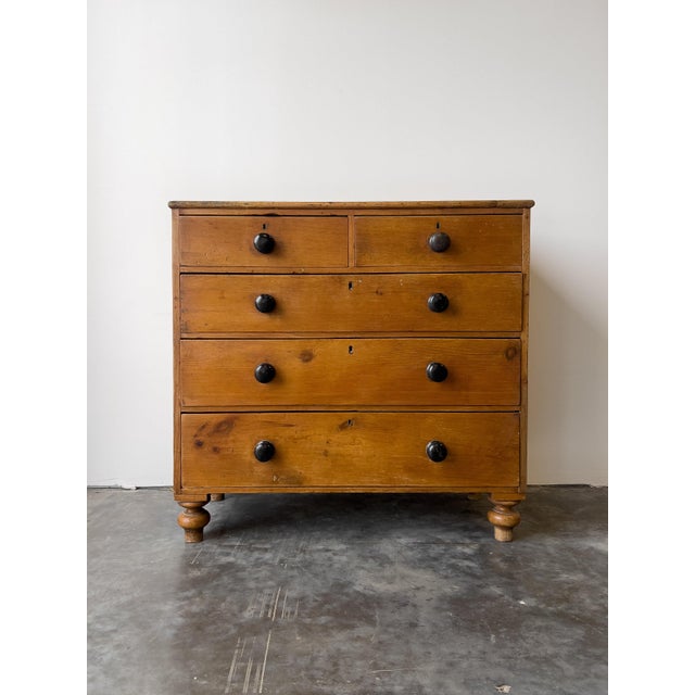 A classic antique 19th century English pine chest of drawers with contrasting black knobs. Two over three drawer...