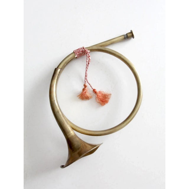 This vintage French brass hunting horn features a classic, understated design with a warm aged patina and braided tassel...