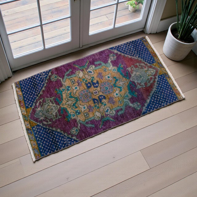 This vintage Turkish small rug presents a richly expressive palette anchored by a deep plum field and balanced with indigo...