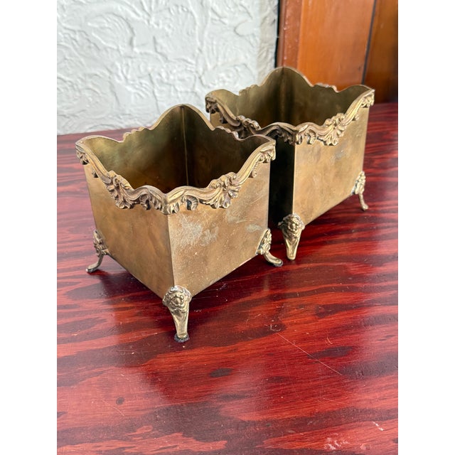 Pair of small square brass cachepots in the Louis XV style. Each has a scalloped rim with rococo scroll and shell trim....
