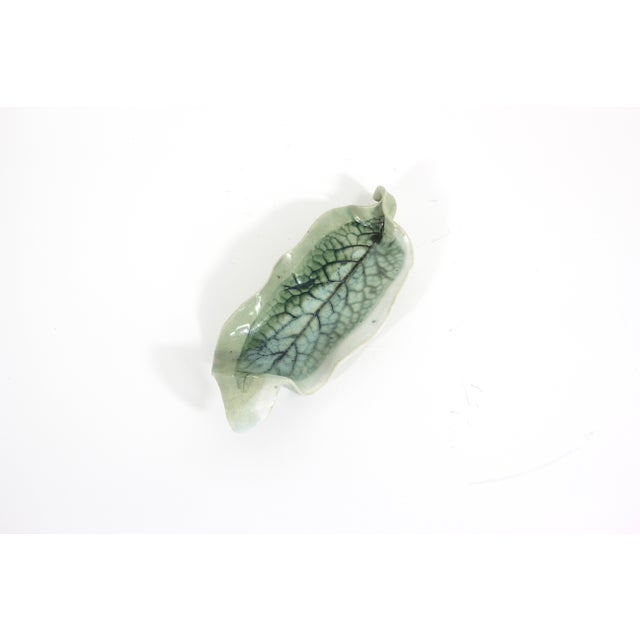 Vintage handmade pottery ceramic dish in the shape of a leaf with green glaze and dark veins. Signed by the artist on the...